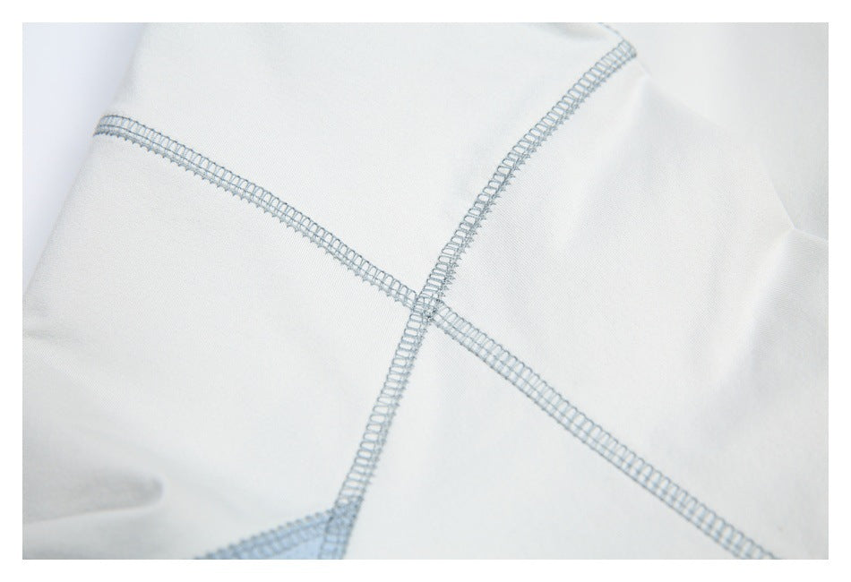 Close-up of white garment fabric with intersecting pale blue overlock seams.