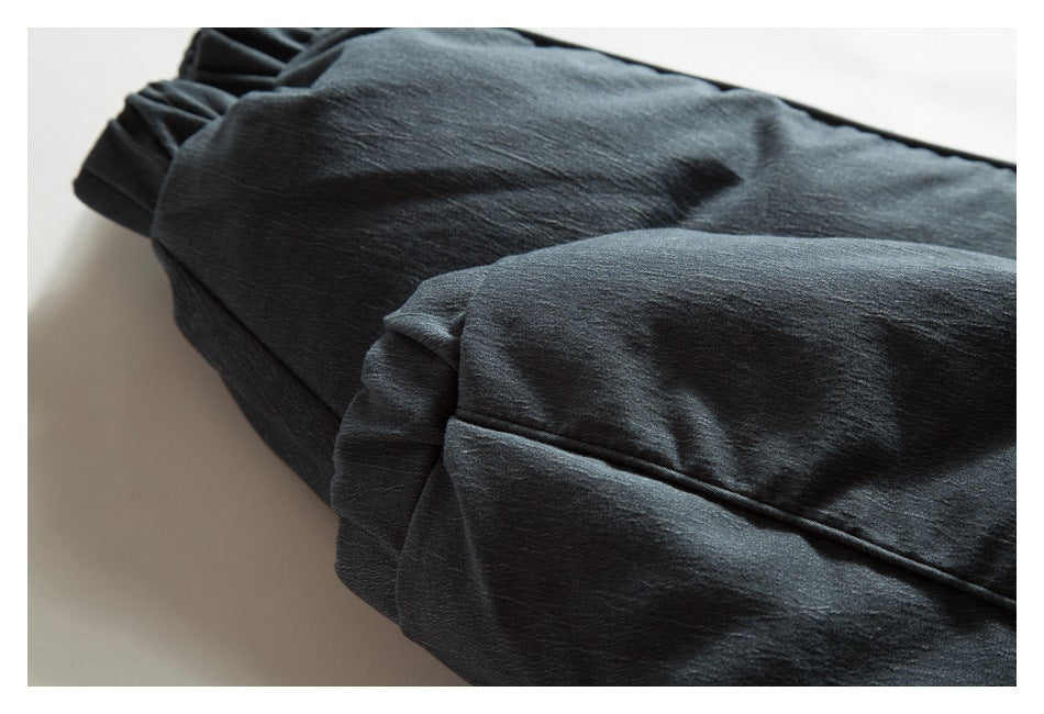 Close-up of dark charcoal jacket fabric with a gathered edge and stitched seam.