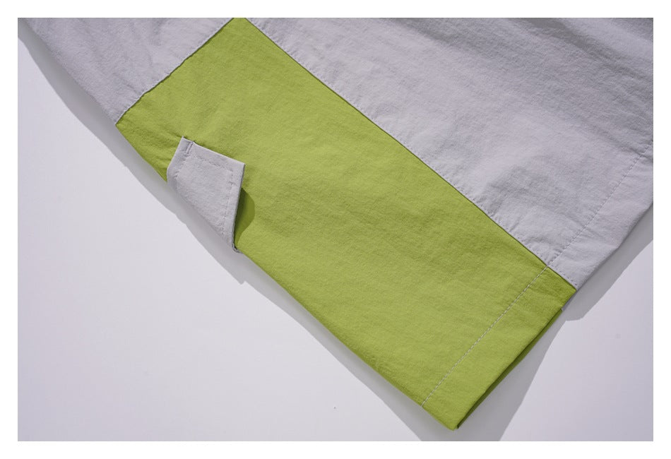 Close-up of light gray bottoms with a broad lime green contrast panel and a small flap detail.