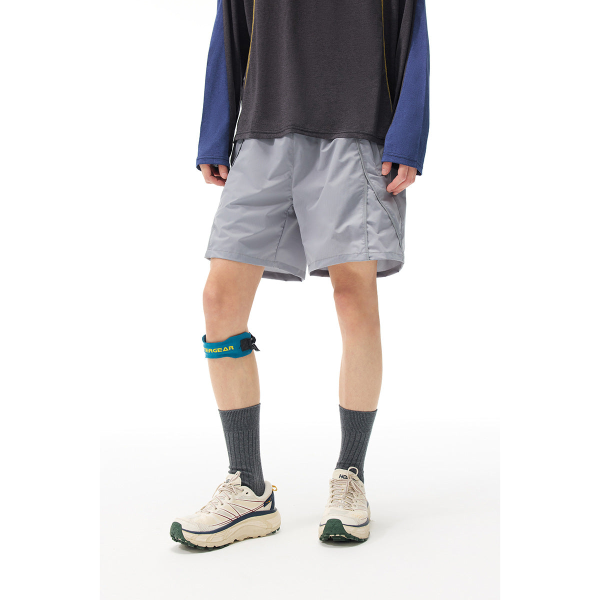Cropped model wearing light gray knee-length athletic shorts with angled pockets and a dark top.