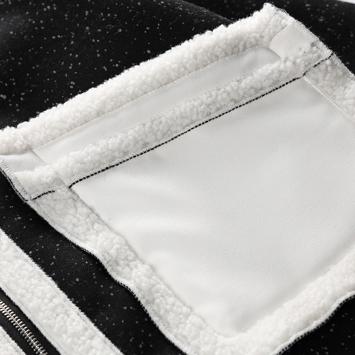 Close-up of the coat interior, showing a broad smooth ivory panel bordered by cream fleece and black flecked fabric.
