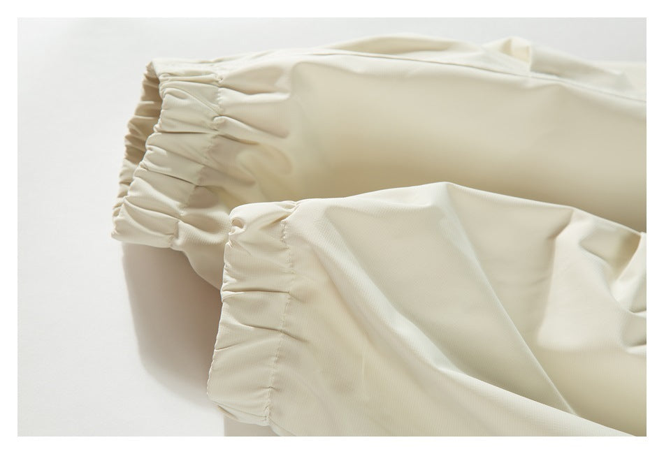 Close-up of two ivory garment sections with gathered elastic edges.