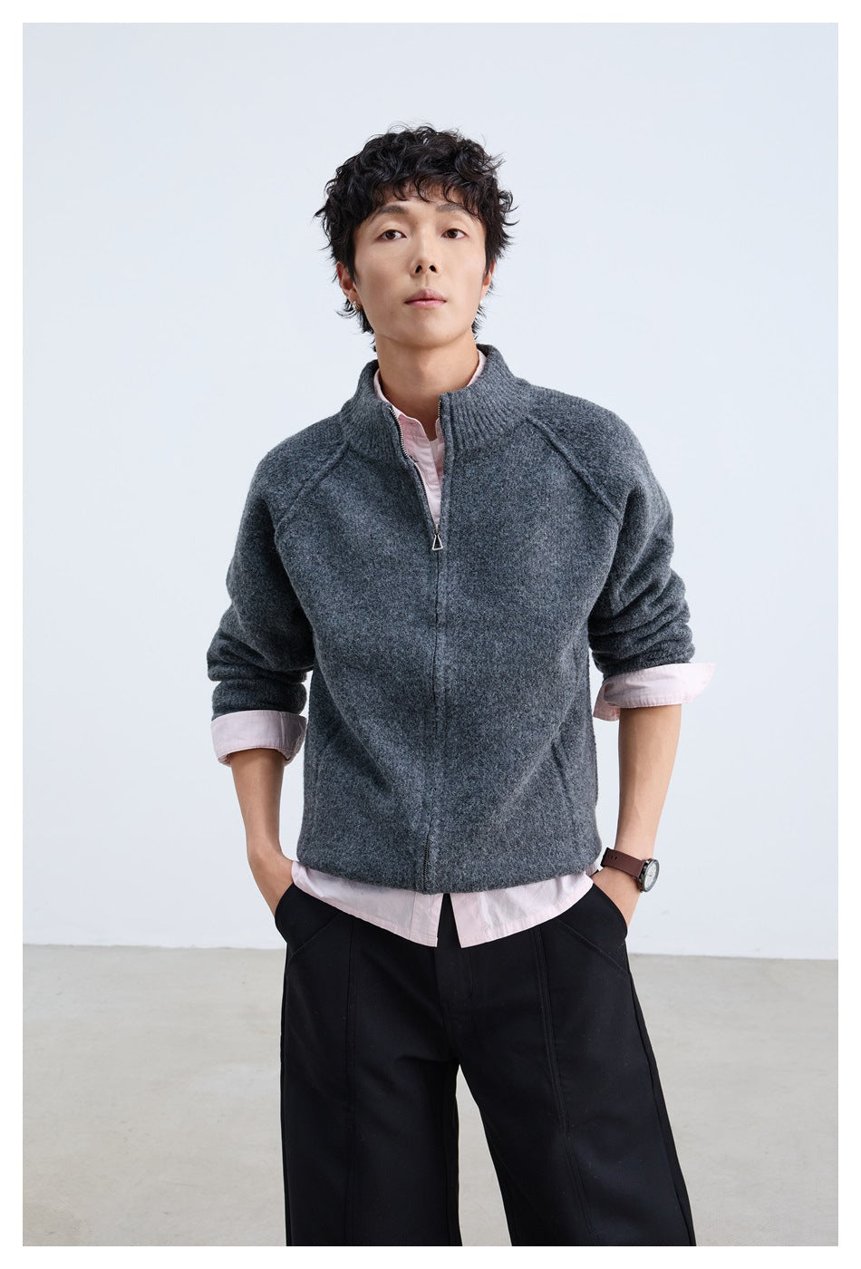 Model wearing a charcoal gray zip-front knit jacket with a ribbed stand collar over a pale pink shirt.
