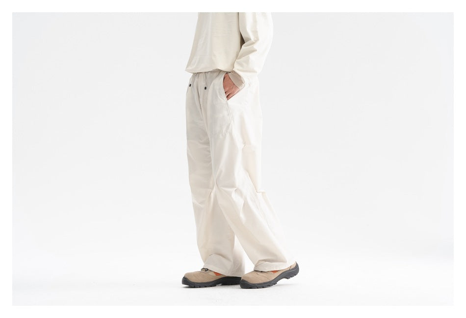 Side view of a model wearing loose cream pants with an elastic waist and a cream top.