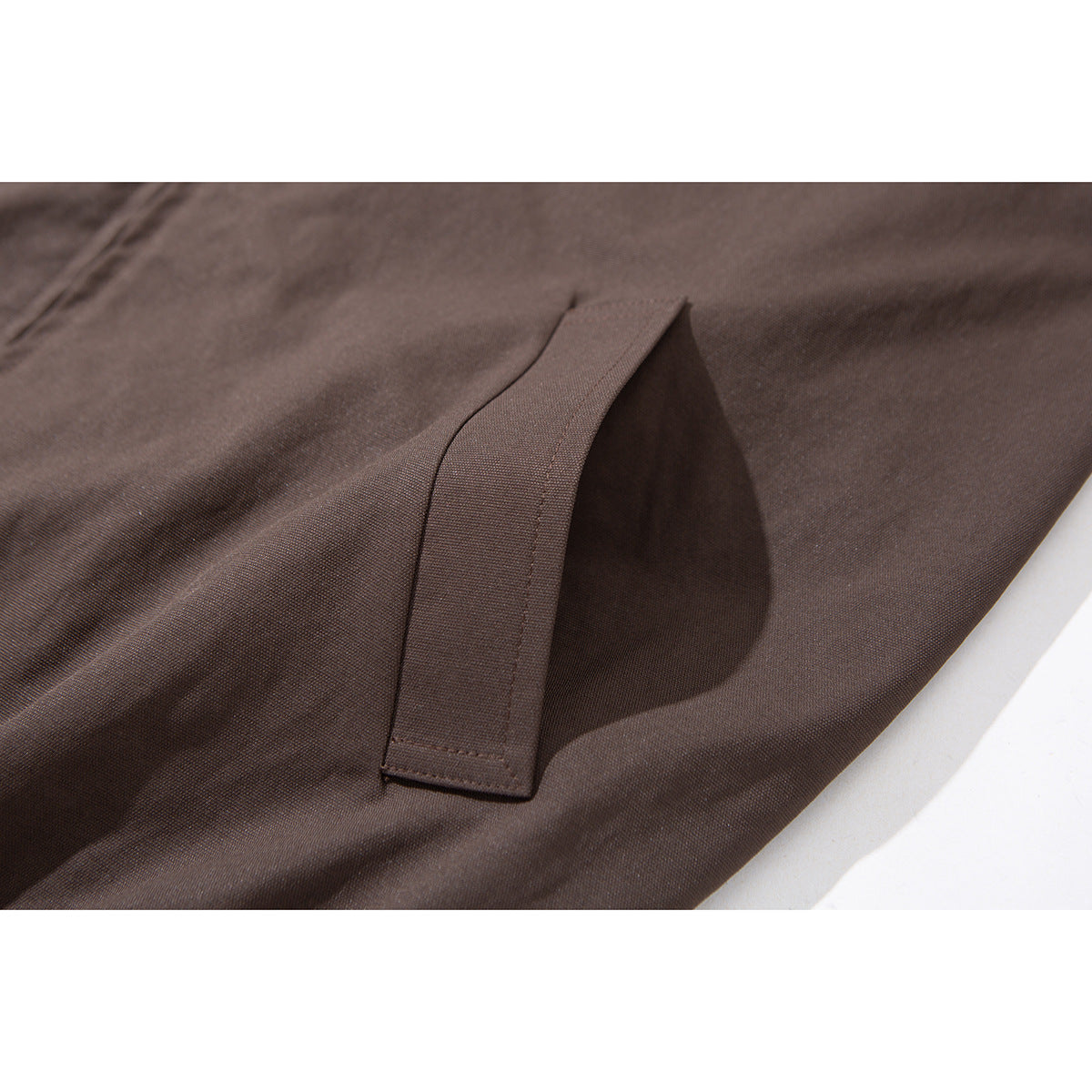 Close-up of a dark brown jacket's angled pocket opening and stitched trim.