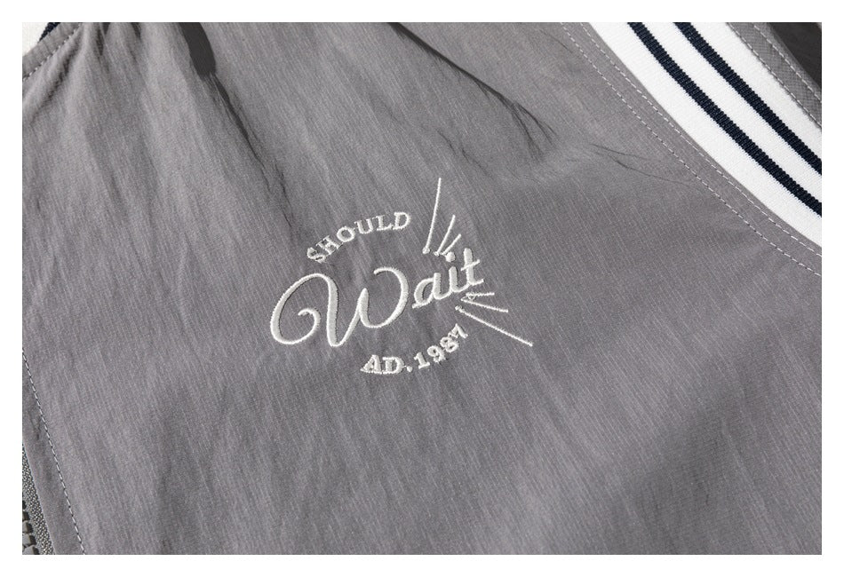 Close-up of white embroidered script and lettering on the gray jacket.