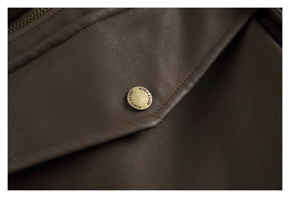 Close-up of a brass-tone button on a stitched pocket flap of a dark brown jacket.