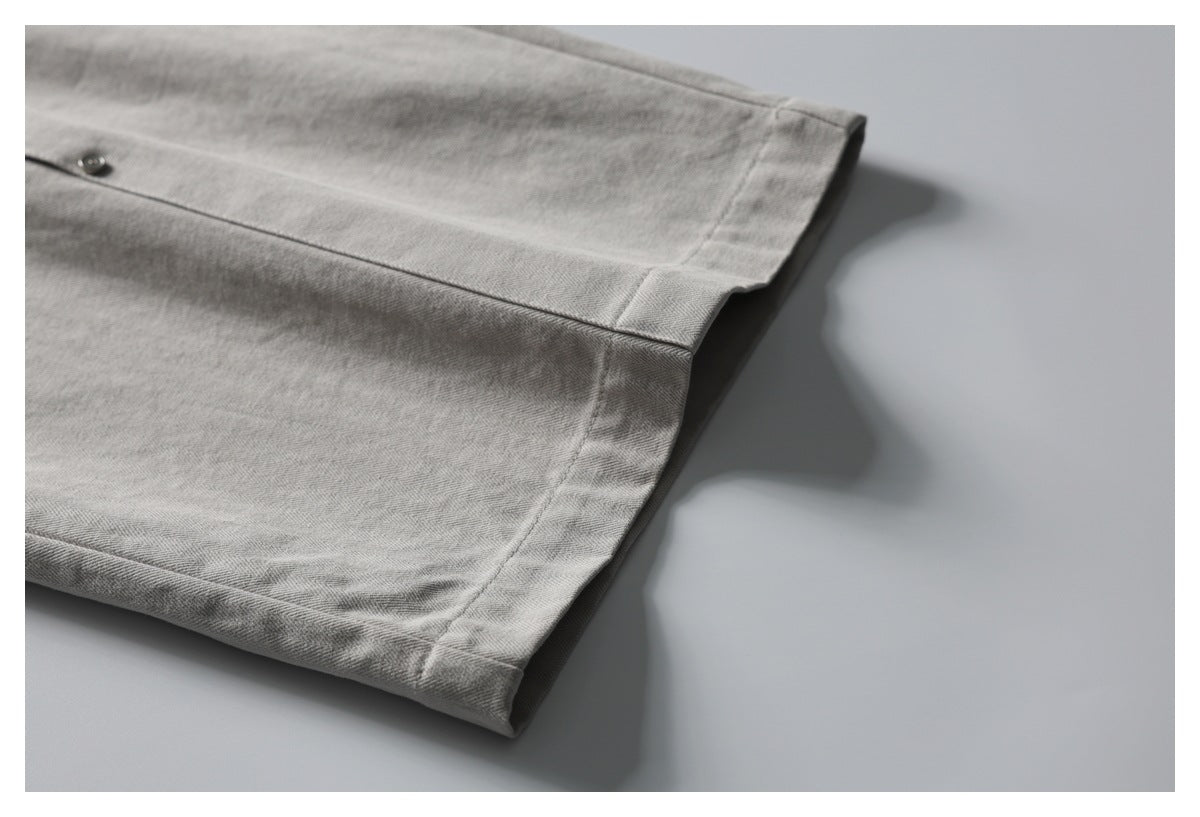 Close-up of the stitched hem on gray herringbone trousers.