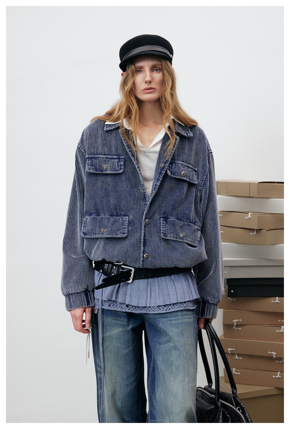 Model wearing a blue ribbed four-pocket jacket over a pleated top and wide-leg jeans.