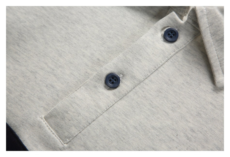 Close-up of two dark buttons and the stitched placket on a light gray heather polo shirt.