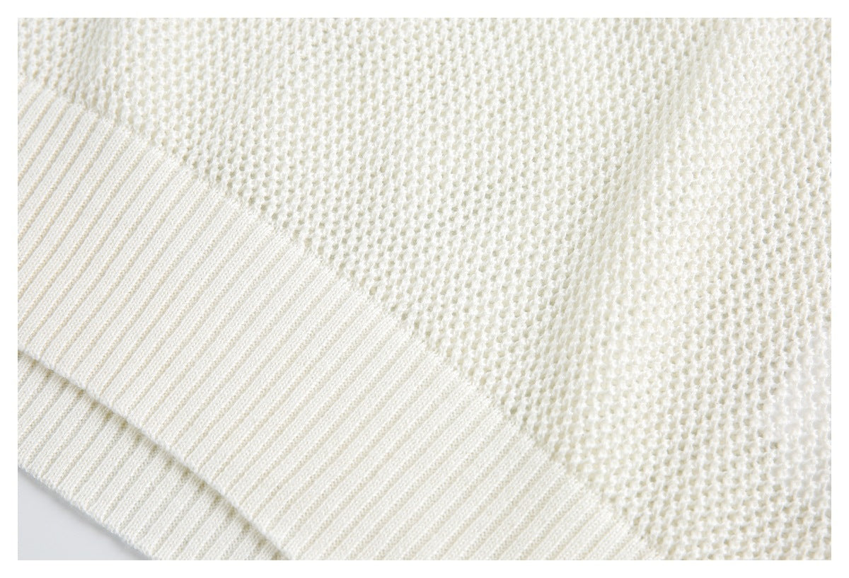 Close-up of an ivory sweater showing textured knit and a wide ribbed edge.