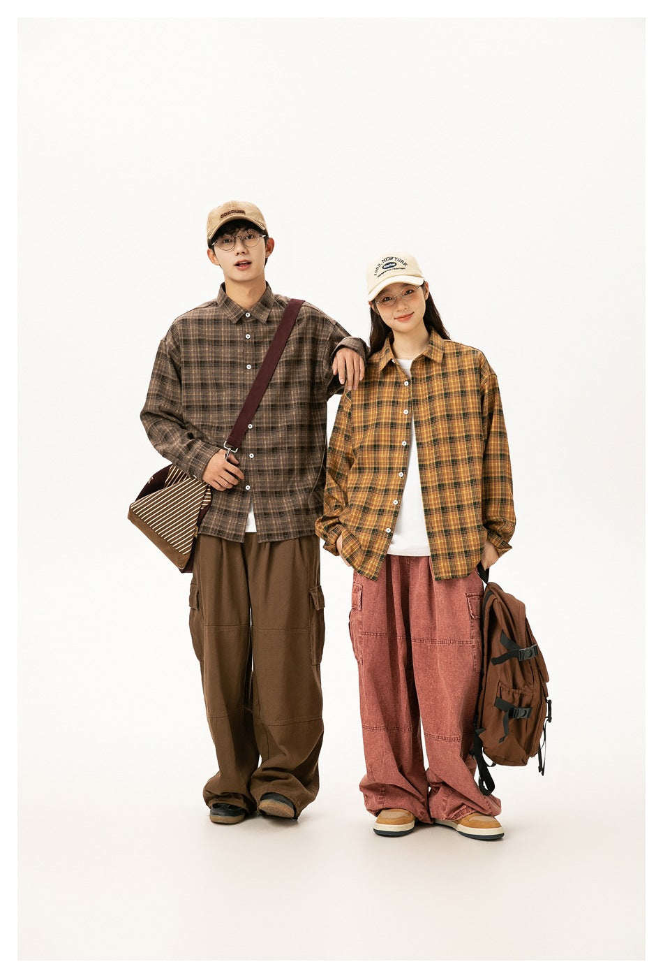 Full-length view of two models wearing brown and mustard plaid shirts with loose cargo pants.