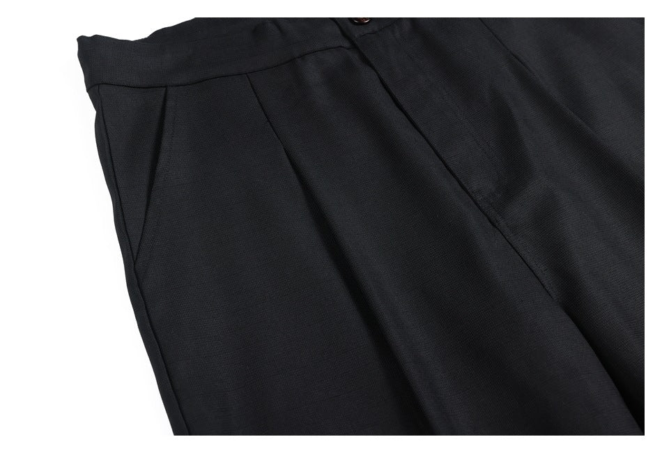 Close-up of black trousers showing a front pleat and angled pocket opening.