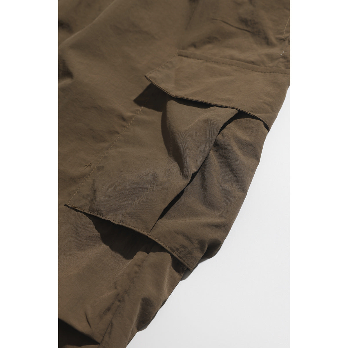 Close-up of a brown cargo pants flap pocket and its layered construction.