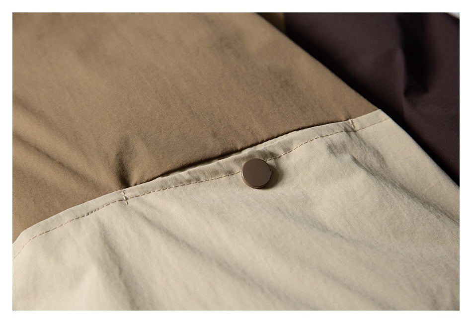 Close-up of a round dark snap fastener on a light beige jacket panel.