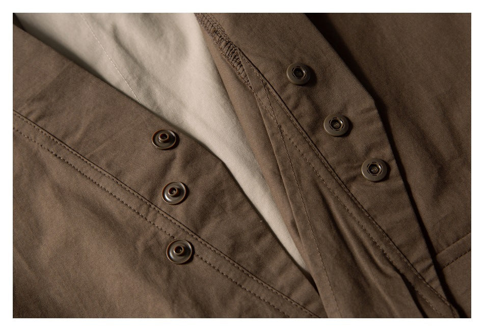 Close-up of a brown garment with dark snap buttons and a light beige contrasting panel.