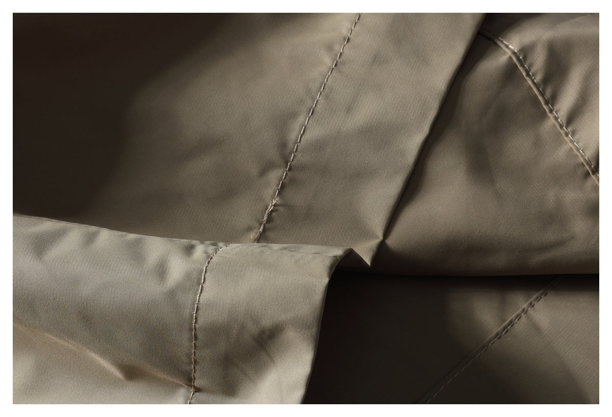 Close-up of taupe trouser fabric showing stitched seams and a folded edge.