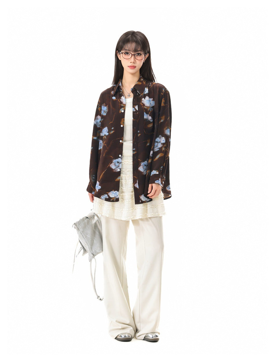 Model wearing the brown blue-floral shirt open over a cream top, lace skirt and white wide-leg pants
