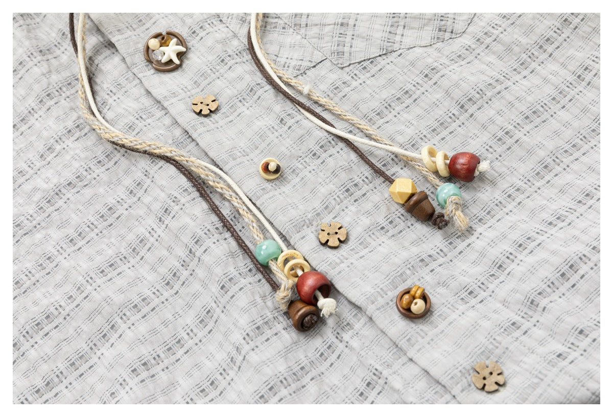 Close-up of the checked jacket front, showing flower-shaped buttons and decorative braided cords with colorful beads.