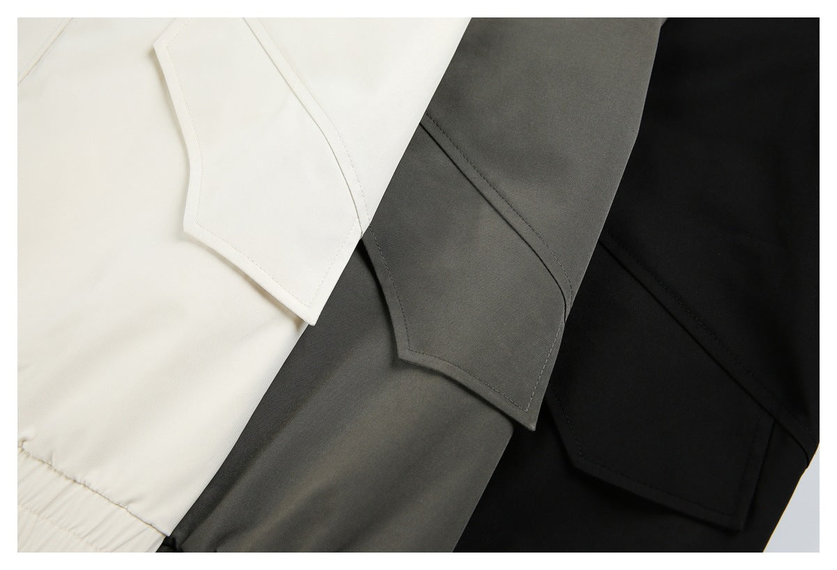 Close-up of cream, dark gray, and black jackets showing stitched sleeve panels and elasticated hems.