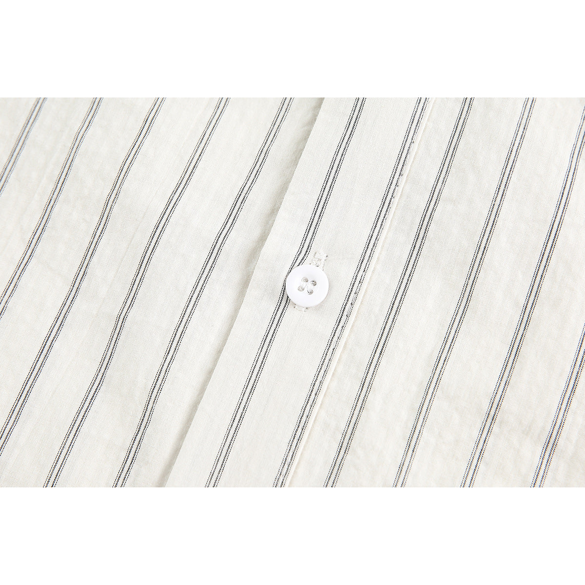Close-up of thin dark stripes and a white button on off-white shirt fabric.