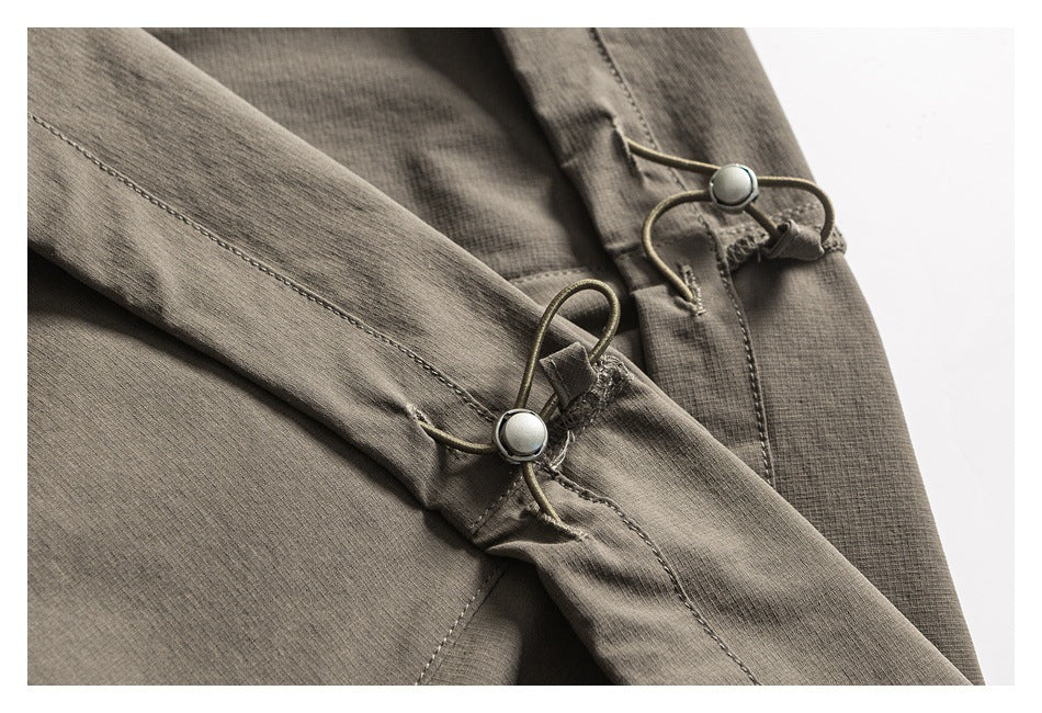 Close-up of a gray-brown garment showing stitched seams and cord-loop fasteners with metal buttons.
