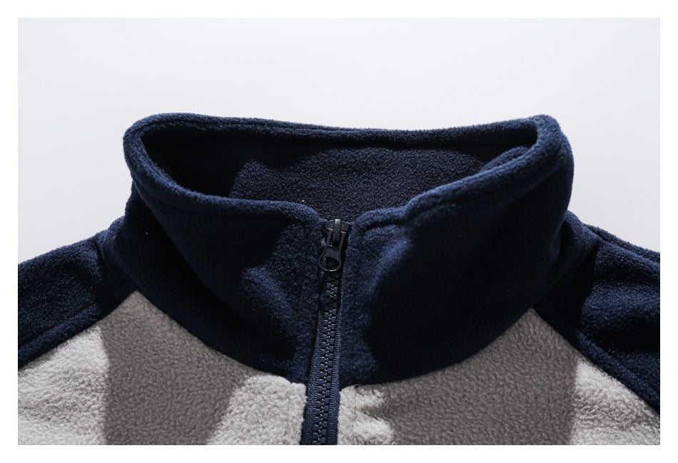 Close-up of a navy stand collar and front zipper on a light gray and navy fleece jacket.