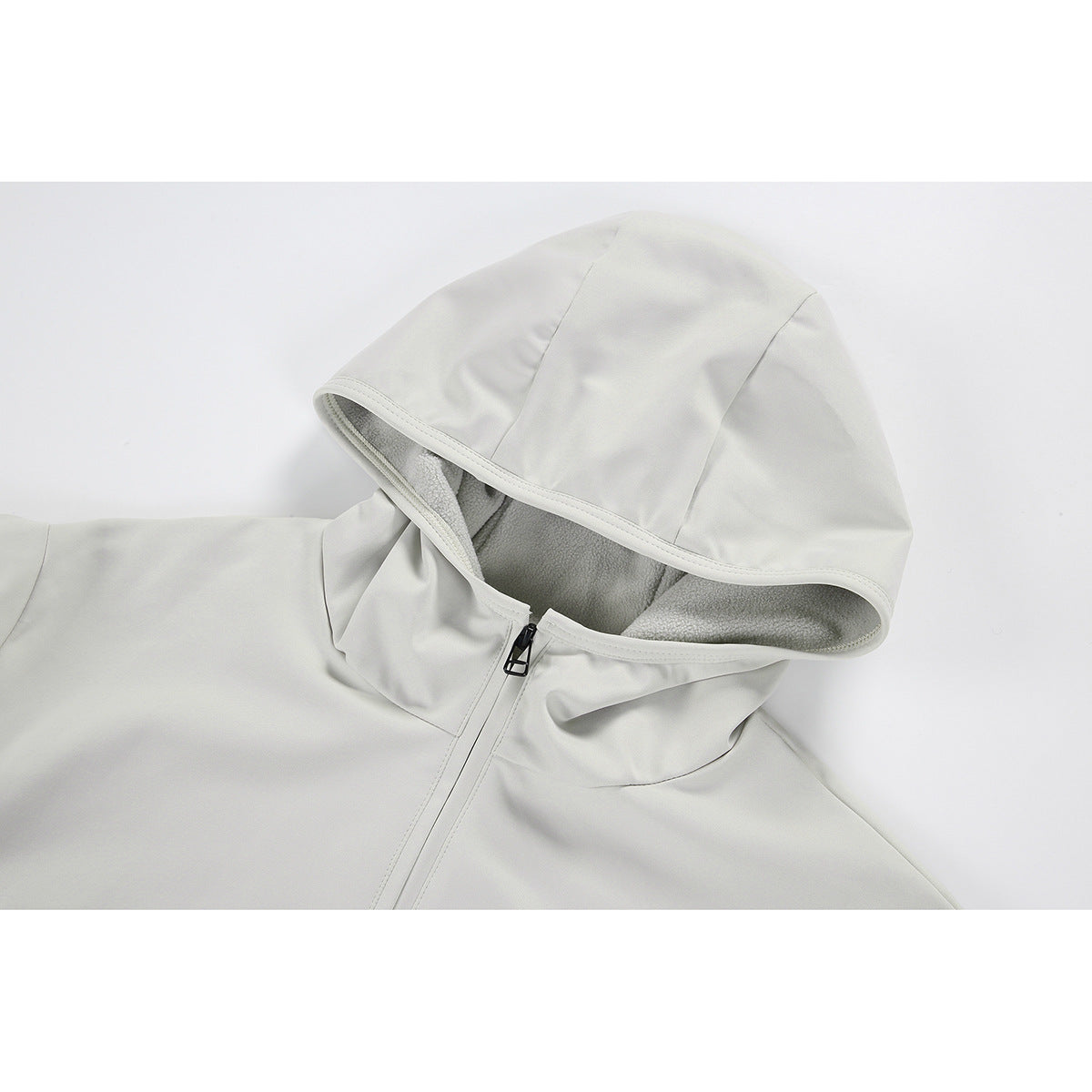 Close-up of an off-white jacket hood with gray lining and a black zipper pull.