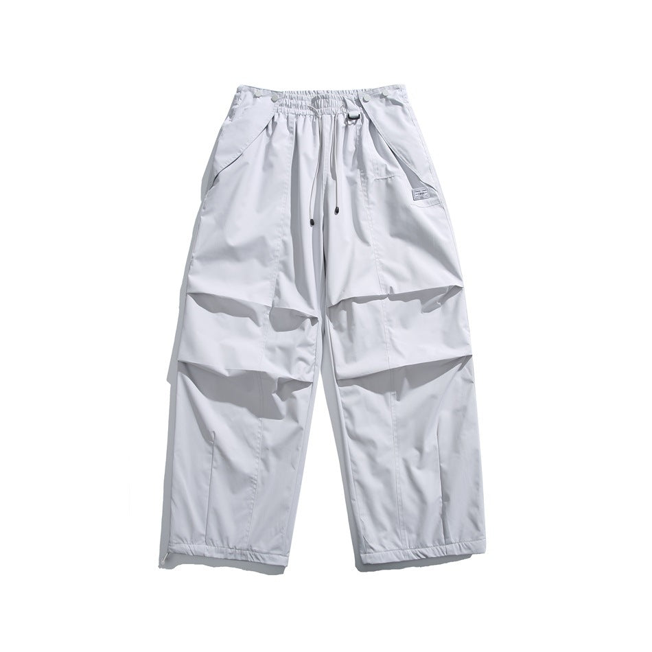 Front view of white wide-leg pants with an elastic drawstring waist, angled pockets, knee panels and ankle hems.