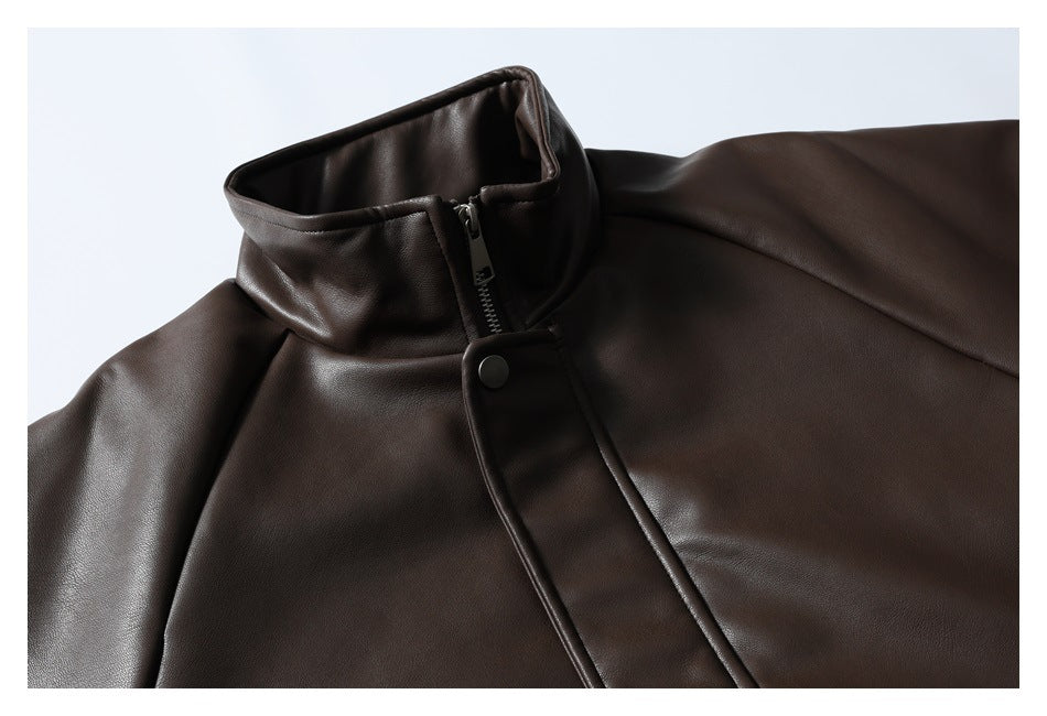 Upper front of a dark brown jacket showing its stand collar, zipper, snap flap and smooth finish.