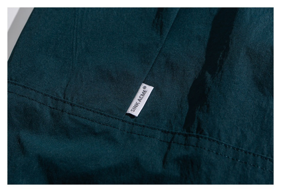 Close-up of a dark teal garment with a stitched seam and a small white sewn-in label.
