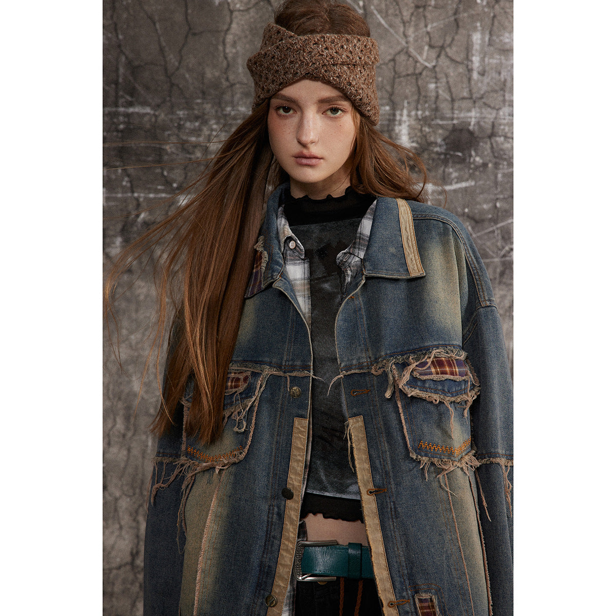 Model wearing an oversized distressed blue denim jacket with frayed plaid-trimmed pockets and tan edging.