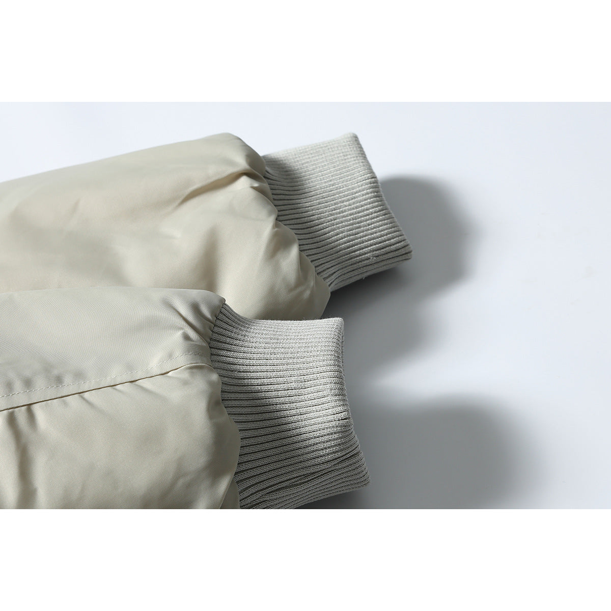 Close-up of the light gray bomber jacket's sleeves and ribbed knit cuffs.