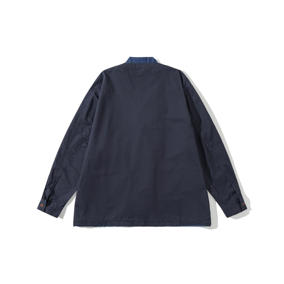 Back view of a flat-laid navy jacket with long sleeves and a blue plaid inner collar peeking above the neckline.
