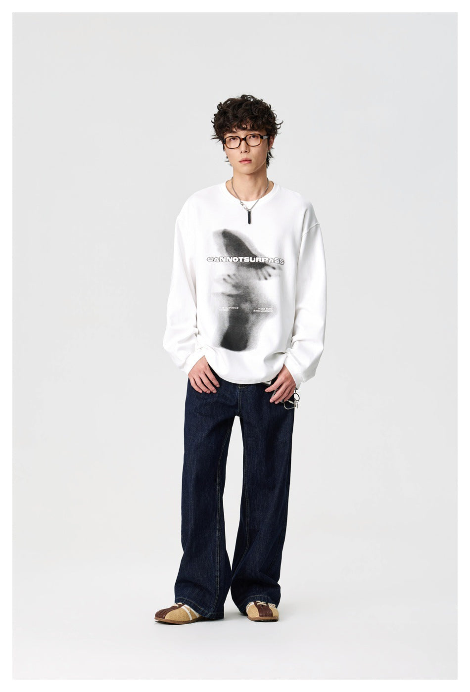 Model wearing a white oversized sweatshirt with a black graphic and text print.