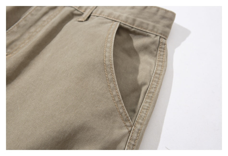 Close-up of beige trousers showing a curved pocket opening and double-stitched seams.