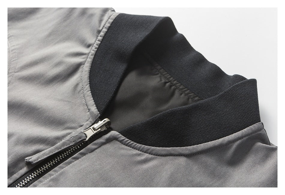 Close-up of a gray jacket’s black rib-knit stand collar and front zipper.