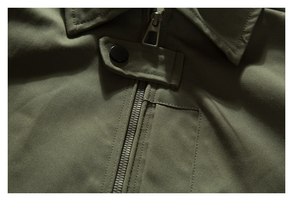Close-up of an olive jacket showing its front zipper, snap-fastened flap and small chest pocket.