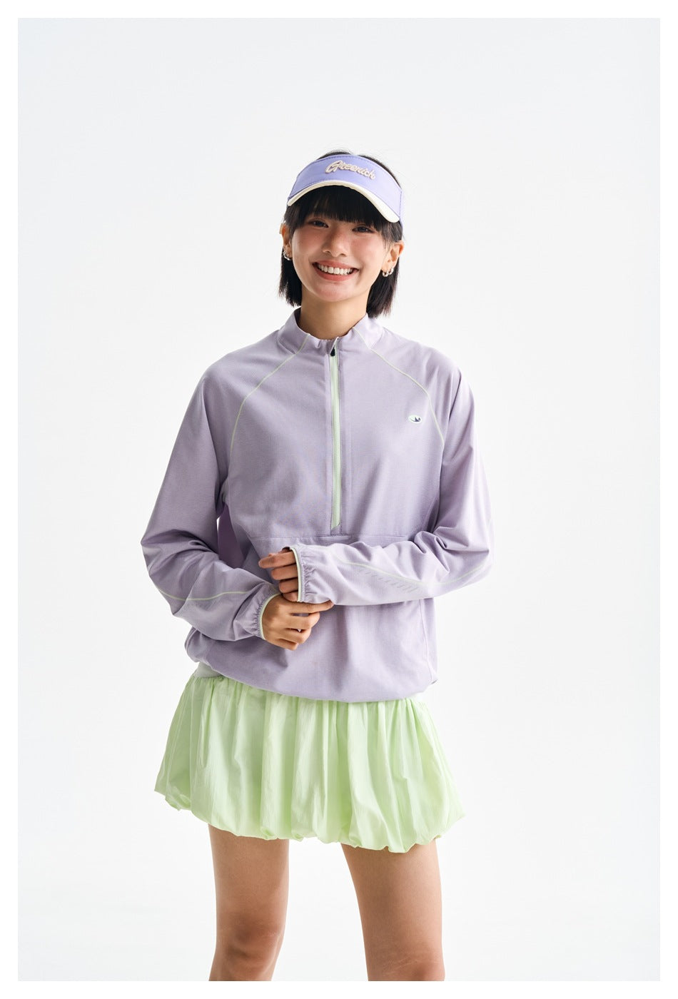 Closer view of a model wearing a lavender half-zip top with pale green contrast trim and a pale green bubble skirt.