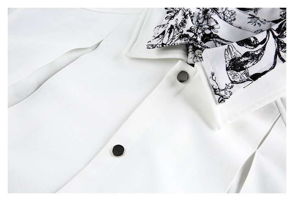 Close-up of a white garment with a black floral-patterned collar lining and dark snap buttons.