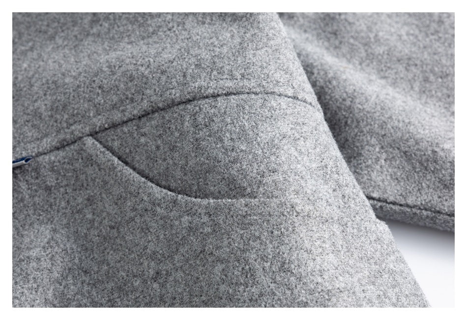 Close-up of gray textured garment fabric with a curved seam and a small zipper edge.