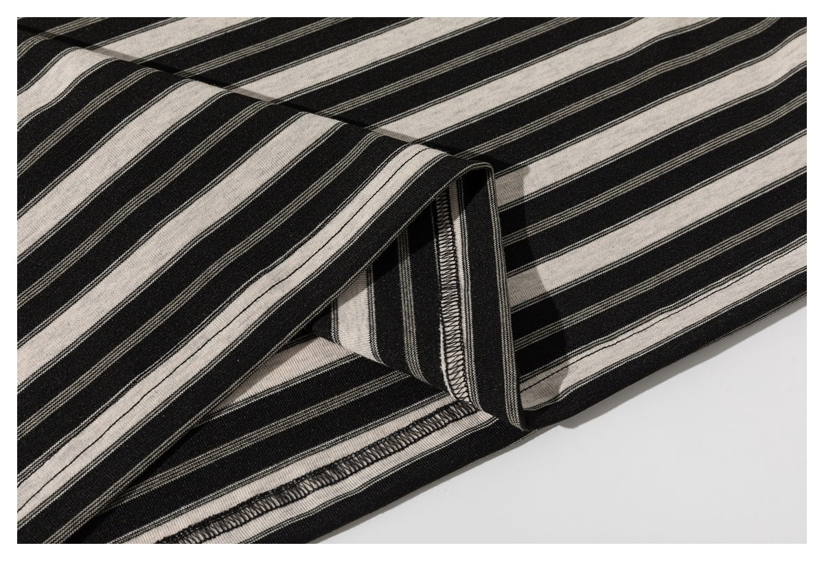 Close-up of a black and cream striped shirt hem with visible overlock stitching.