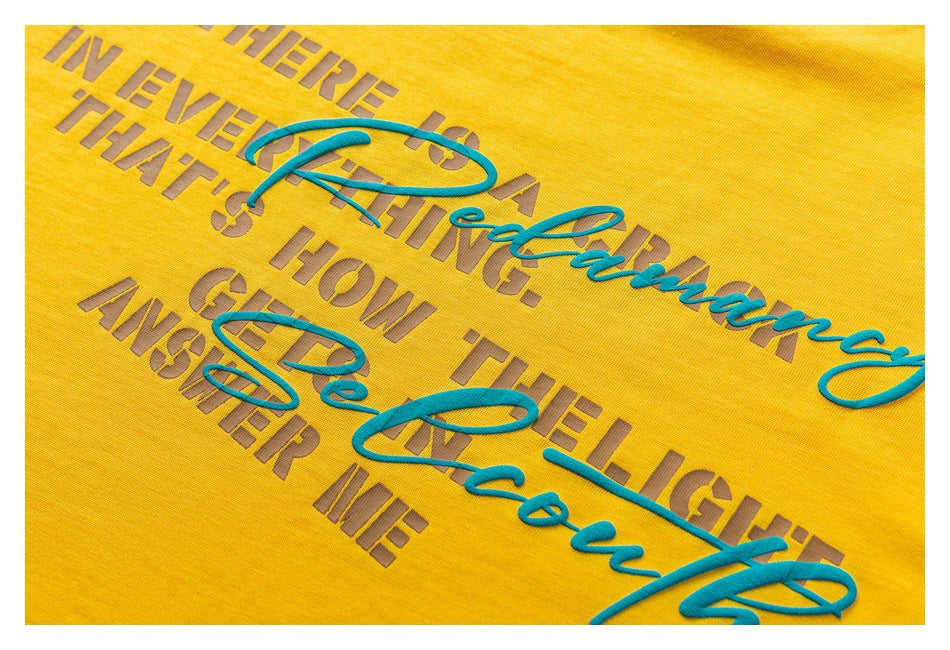 Close-up of a yellow garment with raised teal script and gray English lettering printed on it.