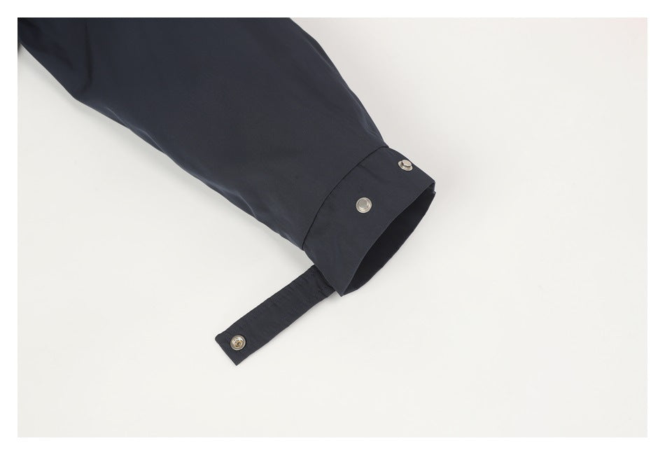 Close-up of a dark jacket sleeve with its snap cuff tab unfastened.