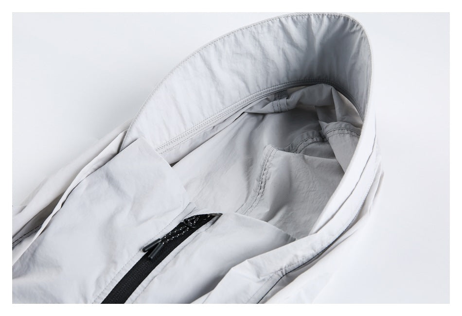 Close-up of a light gray jacket's hood, inner seams, and upper front zipper.