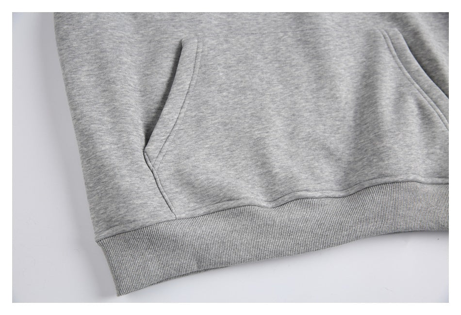 Close-up of the heather-gray hoodie’s front pouch pocket and ribbed waistband.