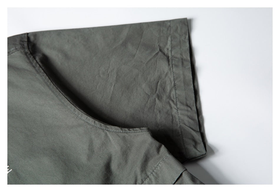 Close-up of a dark gray-green shirt showing a curved seam and folded sleeve or panel edge.