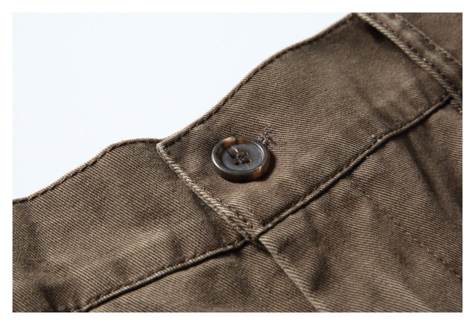 Close-up of brown trousers showing the waistband button, stitching, and diagonal twill texture.