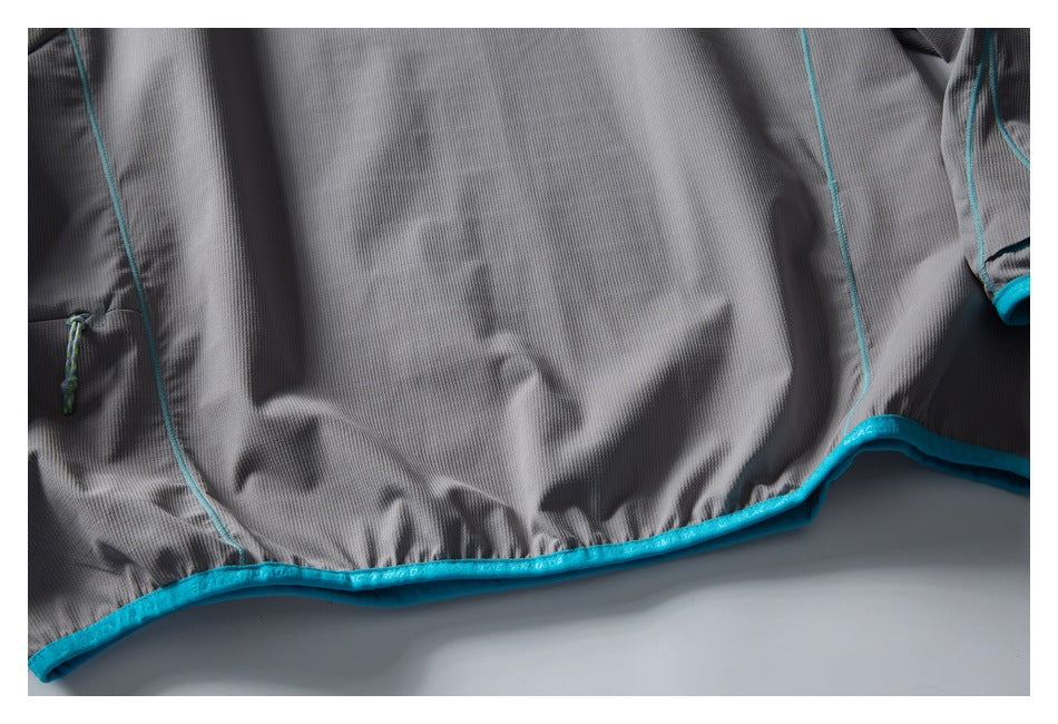 Close-up of the gray pullover’s lower hem, showing turquoise binding, curved seam piping, and a small cord detail.