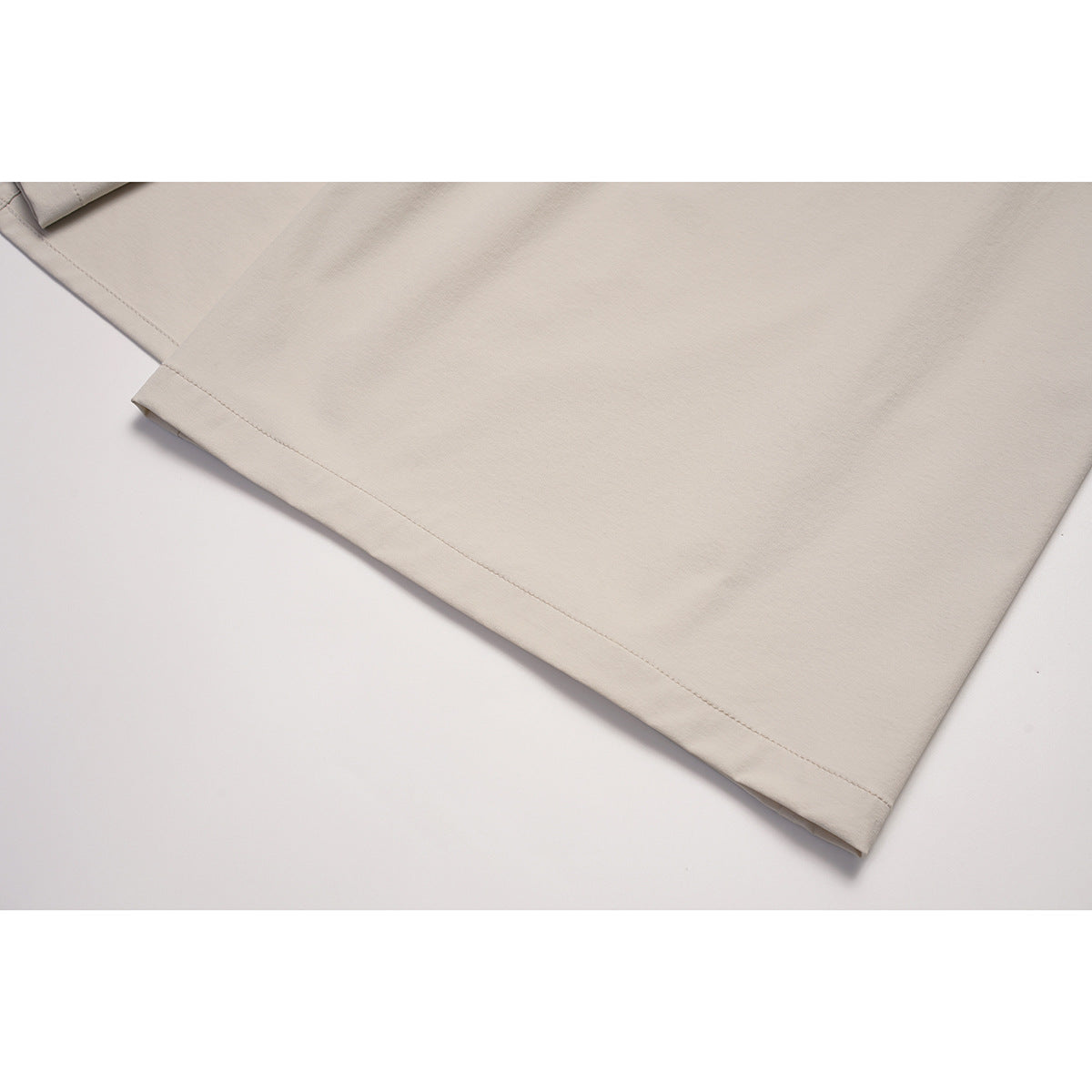 Close-up of the stitched hem on a light beige skirt.